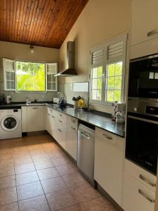 a kitchen with white cabinets and a washer and dryer at Villa Elise Jolie Maison , Piscine, WiFi, pour 7 personnes in Ducos