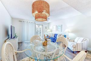een woonkamer met een glazen tafel en stoelen bij Recently updated resort condo with 2 pools, 2 balconies, ocean views, BBQ, & W/D in St. Augustine