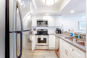 een keuken met witte kasten en een roestvrijstalen koelkast bij Recently updated resort condo with 2 pools, 2 balconies, ocean views, BBQ, & W/D in St. Augustine