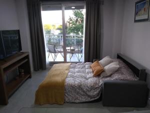 um quarto com uma cama, uma televisão e uma varanda em Dpto Alberdi em Santa Fé