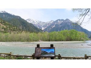 un cartello di fronte a un fiume con montagne sullo sfondo di Nakanoyu Onsen Ryokan - Vacation STAY 06670v a Matsumoto