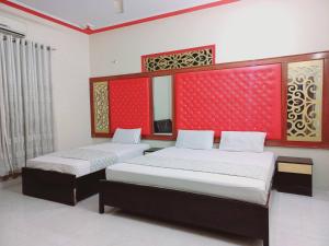 duas camas num quarto com parede vermelha em Rose Palace Millennium em Karachi