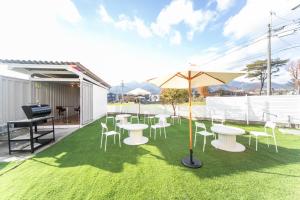 eine Terrasse mit Tischen, Stühlen und einem Sonnenschirm in der Unterkunft Komono Garden Resort - Vacation STAY 06798v 