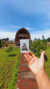 a hand holding up a picture in front of a building at Raturinjani homestay in Selong
