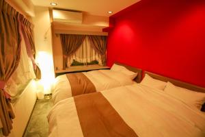 a red bedroom with two beds and a red wall at Fushimi Yokkusu Building 10F - Vacation STAY 16301 in Nagoya