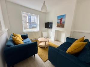 a living room with two blue couches and a table at Buttercup Cottage in St. Leonards