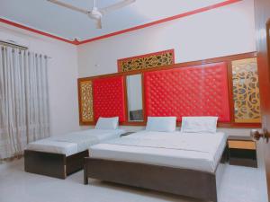 a bedroom with two beds and a red wall at Rose Palace Millennium in Karachi