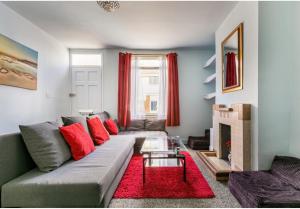 a living room with a gray couch and red pillows at Victoria Cottage-seconds to beach-pet friendly- easy parking- self check in-sleep 6 people-minutes walk to all amenities in Deal