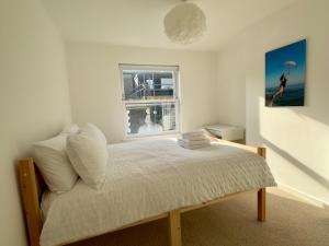 a white bedroom with a bed with a window at Buttercup Cottage in St. Leonards