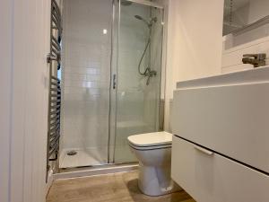 ein Badezimmer mit Toilette und Glasdusche in der Unterkunft Buttercup Cottage Off-Street Parking 2 Large SUVs 3 Minutes to Beach in St. Leonards