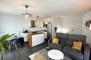 Il comprend un salon avec un canapé et une cuisine. dans l'établissement 040- La Movida - Gare Sud de France * 2chambres, Piscine, Clim, 2Parking, à Lattes