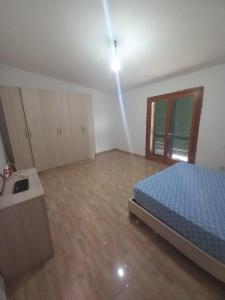 um quarto com uma cama azul e piso em madeira em Vila Toscana em Baks-Rrjoll
