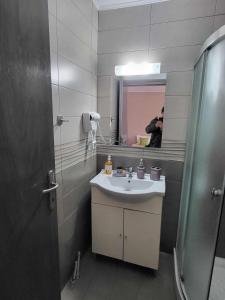 une personne prenant une photo d'une salle de bains avec lavabo dans l'établissement Studio Dimitri Limenaria, à Limenaria