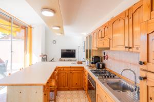 eine Küche mit Holzschränken und einem Waschbecken in der Unterkunft Joly House in Leggiuno