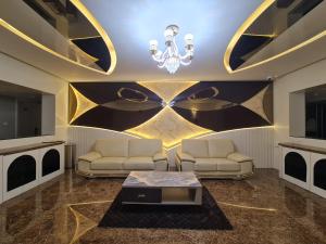 una sala de estar con 2 sofás y una lámpara de araña. en Luxury Hotel Tumkur en Tumkūr