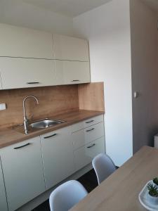 a kitchen with white cabinets and a table and chairs at Klatovy Apartment in Klatovy
