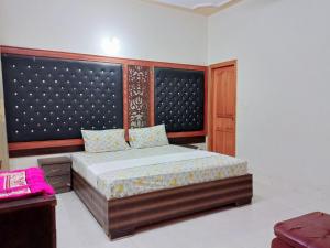 a bedroom with a bed with a large headboard at Rose Palace Guest House in Karachi