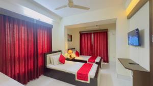a bedroom with two beds and a red curtain at Hotel Grand Circle Inn Dhaka in Dhaka