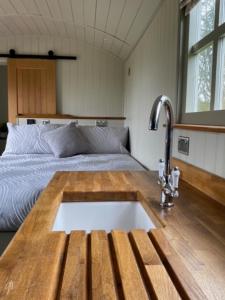 a kitchen with a sink in front of a bed at Woodpecker Shepherds Hut in Boston