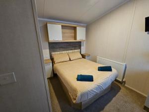 a small bedroom with a bed with two blue pillows on it at Rockley Park, The Poplars in Lytchett Minster
