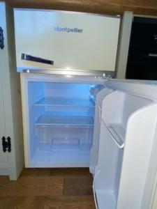 an empty refrigerator with its door open in a room at Woodpecker Shepherds Hut in Boston