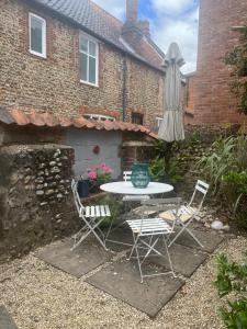 a table and chairs and an umbrella in front of a house at Cromwell Cottage in Fakenham