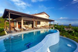 a villa with a swimming pool in front of a house at Gone Tropical Luxury Villa in Soufrière