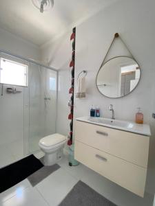 een badkamer met een toilet, een wastafel en een spiegel bij CURTA! | Charmoso sobrado 7min da Expoville in Joinville
