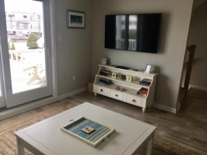 Una sala de estar con televisión y una mesa de café. en New Ocean Block Duplex, en Beach Haven