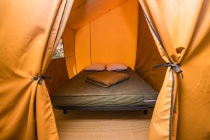 a small bed in a tent with curtains at Camping Onlycamp Sous les Pommiers in Trévières +13 photos