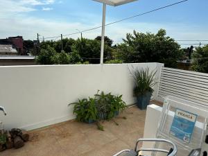 eine Terrasse mit Stühlen und einem Sonnenschirm auf einem weißen Zaun in der Unterkunft Impecable apartamento a 5 minutos de la terminal in Artigas