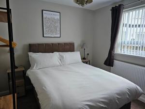 a bedroom with a bed with white sheets and a window at The Ivernia hotel in Skegness