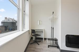 Habitación blanca con escritorio y ventana en The Olive Suite, en Ilkeston