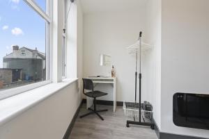 a white room with a desk and a window at The Olive Suite in Ilkeston