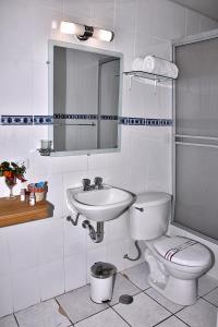 een badkamer met een wastafel, een toilet en een spiegel bij TerraMistica Colca in Coporaque