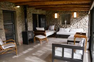 a living room with couches and chairs in a stone wall at Cottage de los Andes in Mendoza