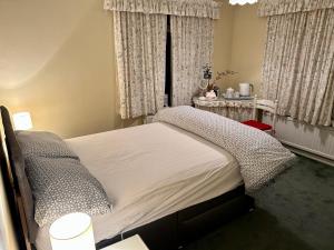 a bedroom with a bed and a window with curtains at Curlews in Feock
