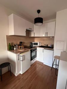 een keuken met witte kasten en een houten vloer bij Appartement 2 pièces Bois d’Arcy in Bois-dʼArcy