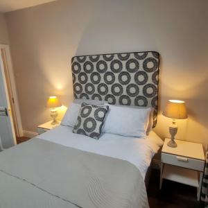 a bedroom with a white bed with a headboard and two lamps at Russell Mews in Ennis
