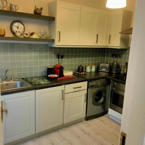 a kitchen with white cabinets and a sink and a dishwasher at Russell Mews in Ennis