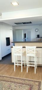 een keuken met twee witte stoelen en een tafel bij 3-Zimmer- Wohnung in Traun, nähe Linz und Wels in Linz