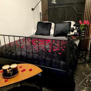 a black bed with red flowers on it with a table at MAGIC HILLS in Ustroń