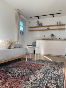 a bedroom with a bed and a table and a rug at The Conservatory, a cosy holiday home located central between Gent Antwerpen & Brussel in Lokeren
