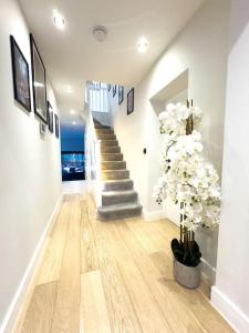 a hallway with a staircase with white flowers in a house at Luxurious 4 Bedroom with patio in Edgware