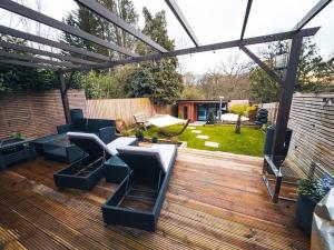 a backyard with a wooden deck with a pergola at Luxurious 4 Bedroom with patio in Edgware