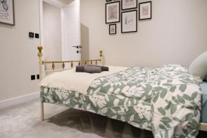 a bedroom with a bed with a green and white comforter at Luxurious 4 Bedroom with patio in Edgware