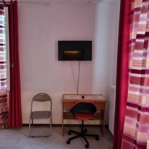 uma secretária com uma cadeira e uma televisão na parede em Room e Breakfast Diana e Ninni Salsomaggiore Terme em Salsomaggiore Terme