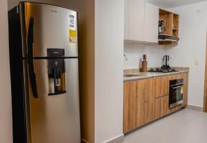 a stainless steel refrigerator in a kitchen with wooden cabinets at Exclusive Luxury Jr Suite 1BRD By ENCOR in Gaira
