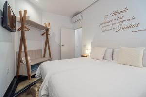um quarto branco com uma cama e uma televisão em Apartamentos CMDreams Gold- ruinas romanas a tus pies- parking privado em Mérida