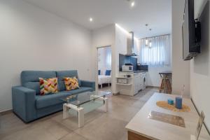 a living room with a blue couch and a kitchen at CMDreams Gold- Apartamentos turísticos con ruinas romanas en el centro de Mérida in Mérida